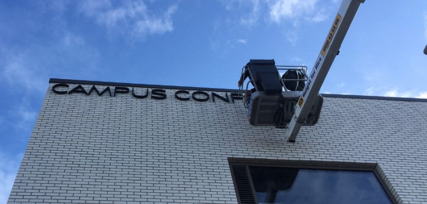 Installation crew in a hoist fitting a sign